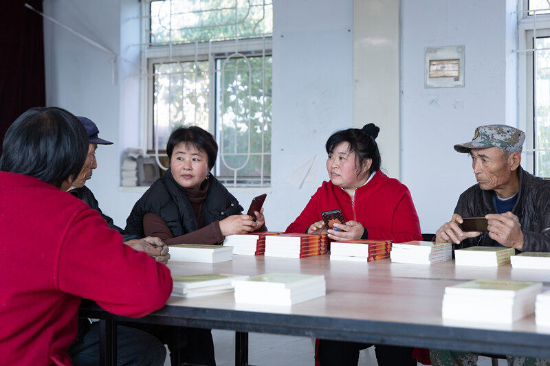 党员志愿者金娜（右二）正在和老党员们分享学习强国平台的当日推荐。