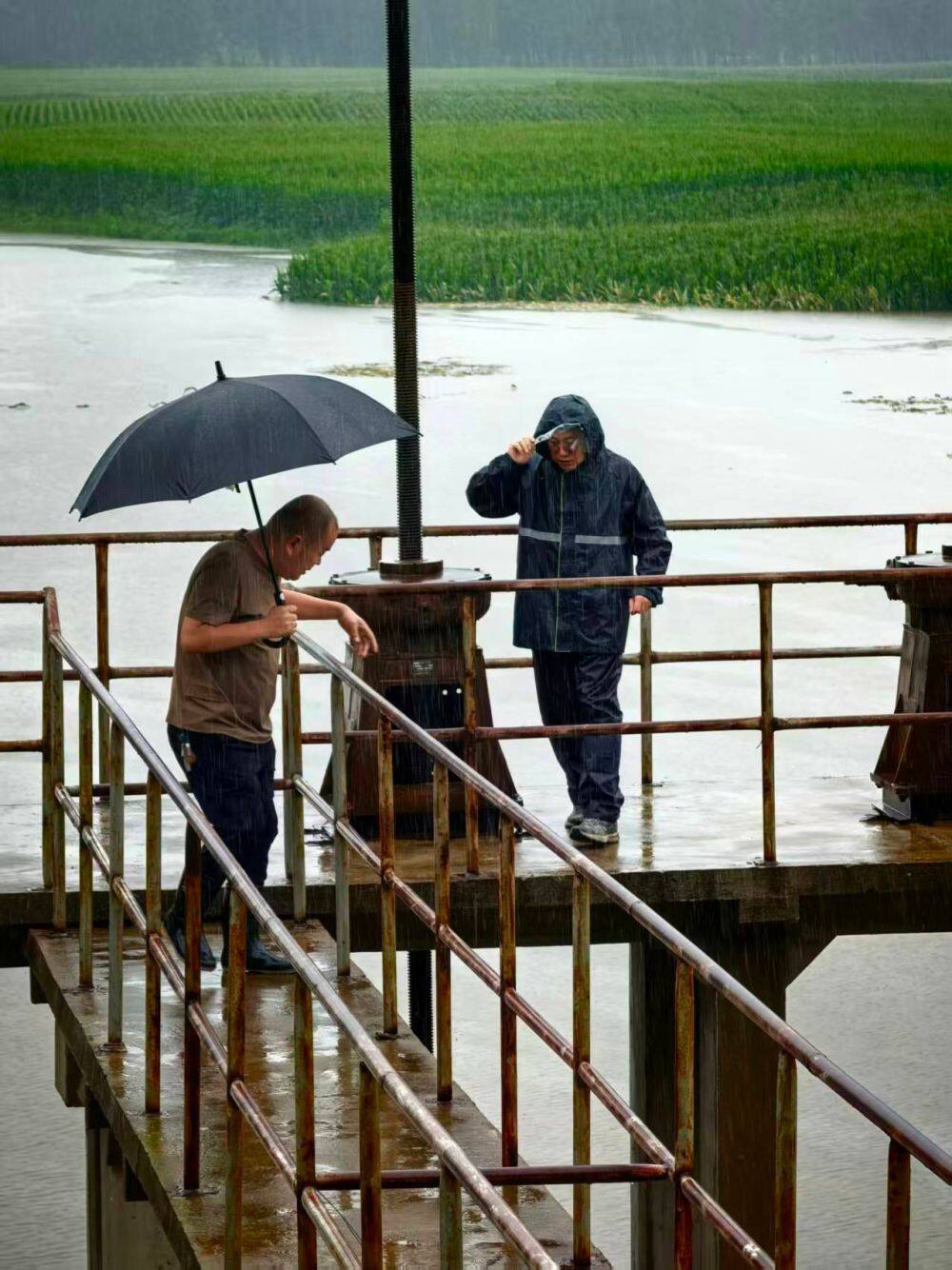 7月13日，王天贺（左）到湘水排水站查看水情。新华社发
